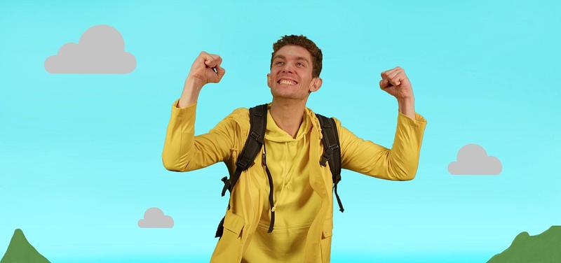 Mac in a yellow jacket looking triumphant, with a blue sky background